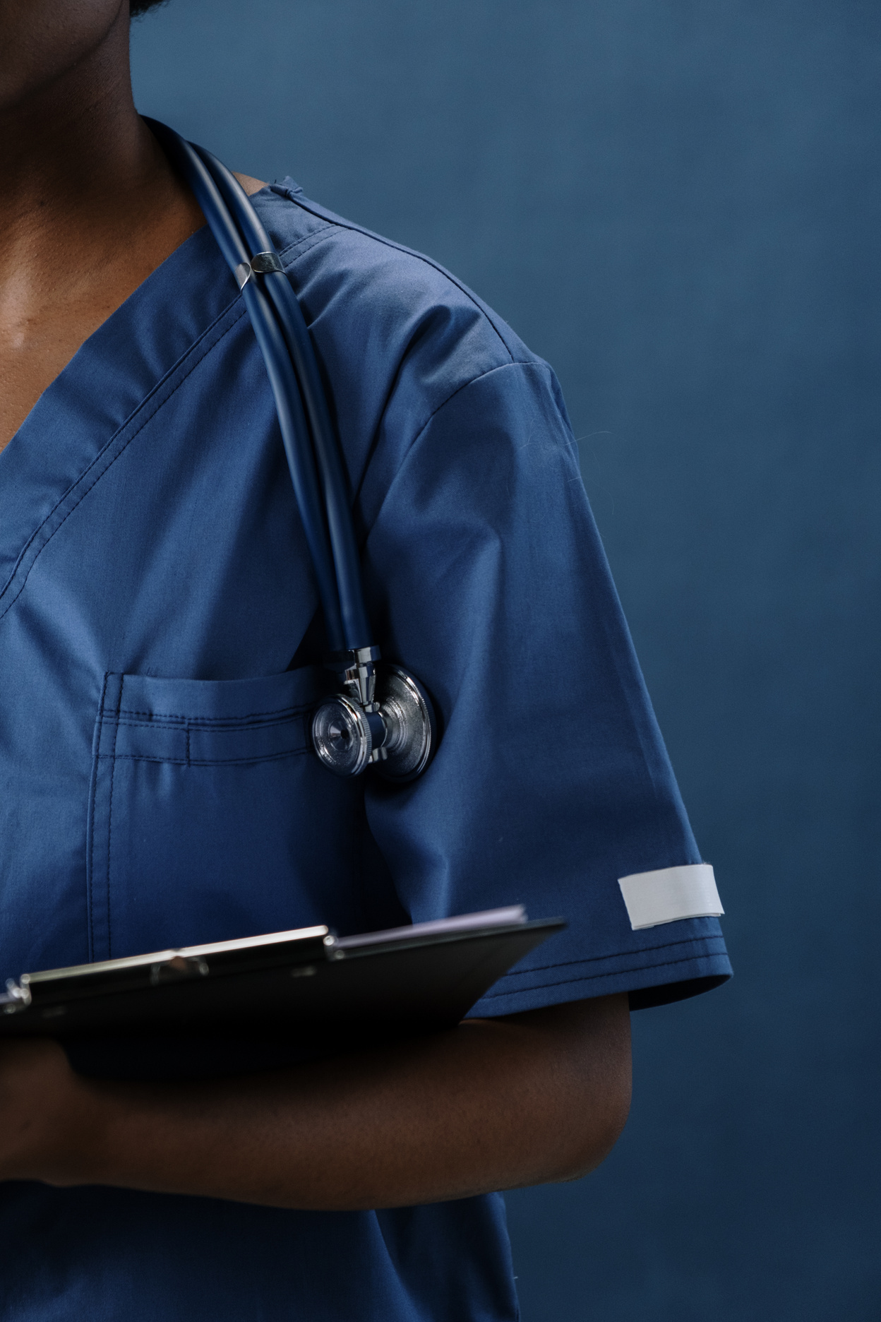 a person in a blue scrub suit holding a clipboard