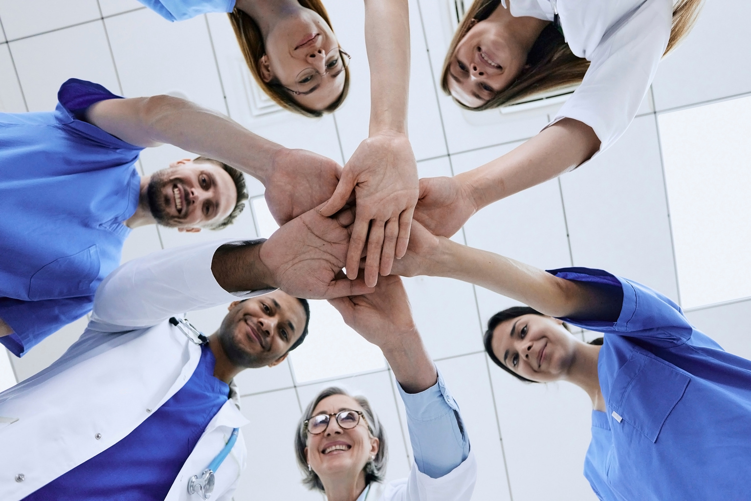 a group of people in scrubs putting their hands together