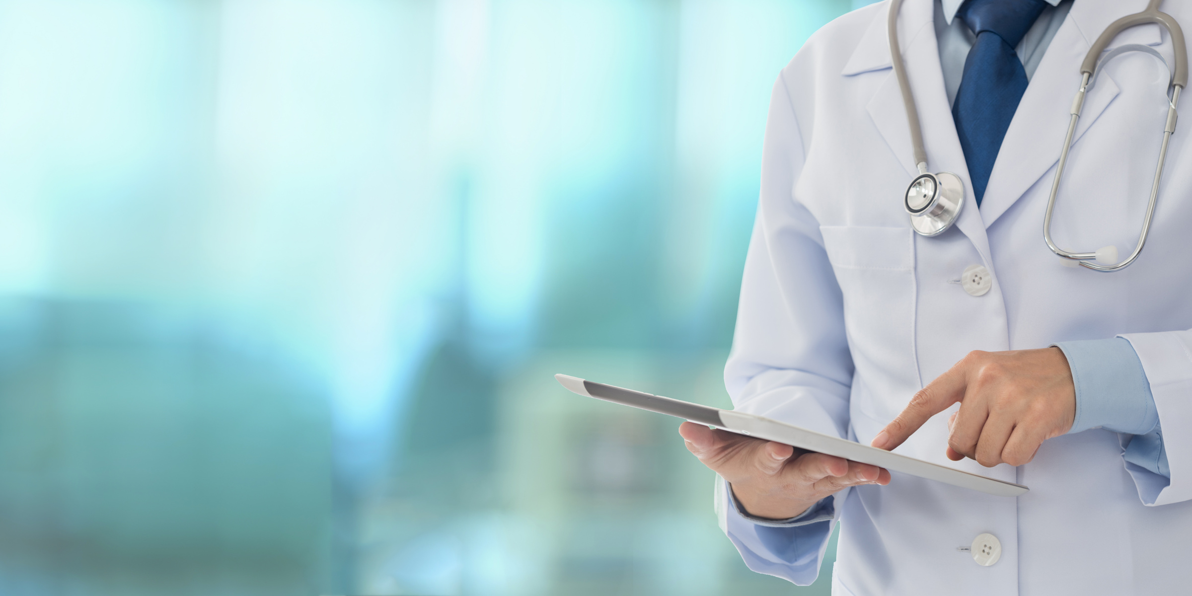 a person or doctor in a lab coat is holding a tablet.